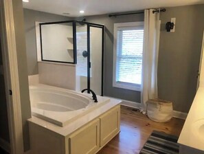 Ein Badezimmer mit einer freistehenden Badewanne, einem Fenster mit Jalousien und einer Duschkabine.
