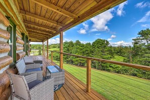 Eine Holzterrasse mit Korbmöbeln und Blick auf eine grüne Landschaft.