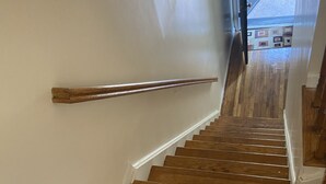 Een houten trap met een leuning, die naar een verdieping leidt.