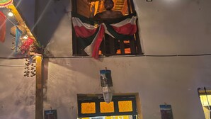 Un edificio con una ventana adornada con una bandera, luces y un farolillo.