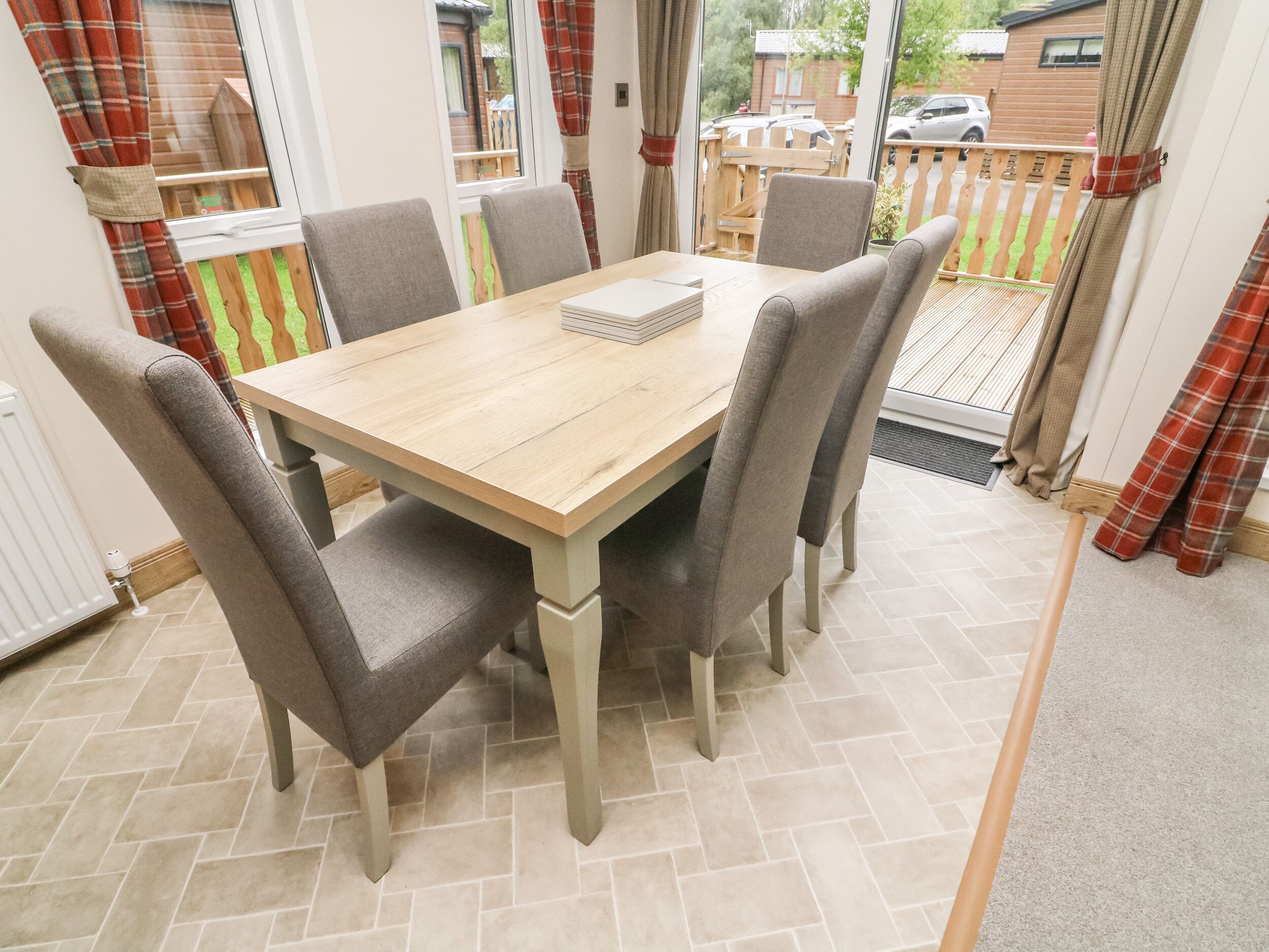 A dining area with a wooden table and six grey upholstered chairs.