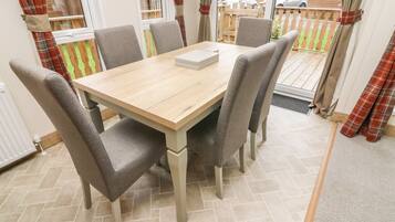 A dining area with a wooden table and six grey upholstered chairs.