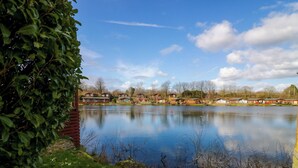 A lakeside view with wooden cabins and a grassy area.