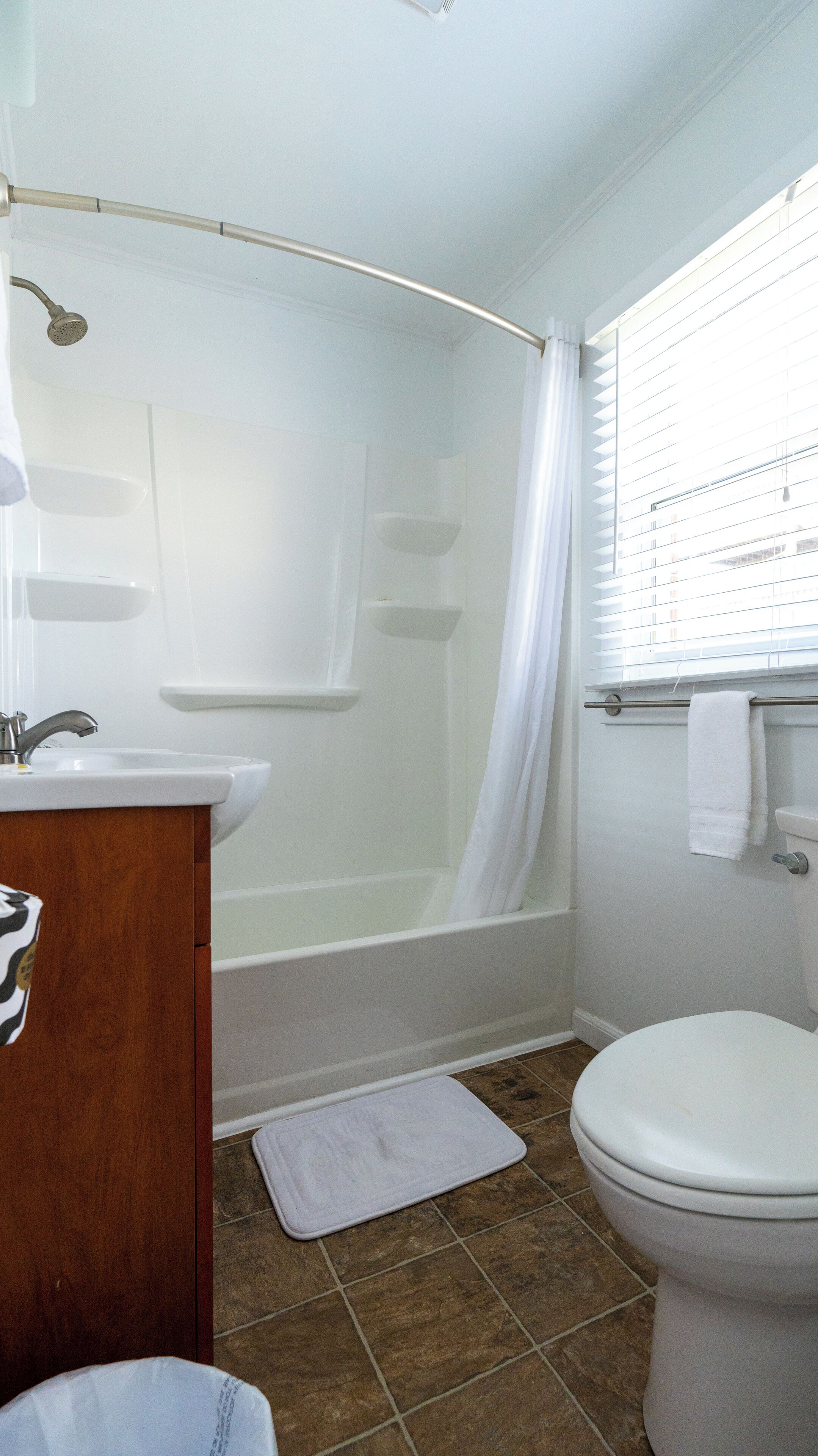 Un baño con bañera, inodoro, lavabo y una ventana con persianas.