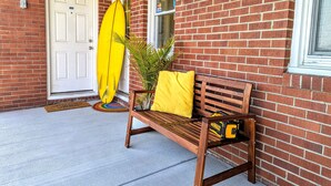 Un banc en bois avec un coussin jaune et une boîte à outils jaune, adossé à un mur de briques.