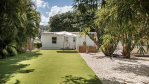 Una casa con césped cuidado, una pequeña terraza y un cobertizo.