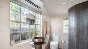 Un baño con un ventanal grande, un lavabo redondo, un inodoro y una zona de ducha.