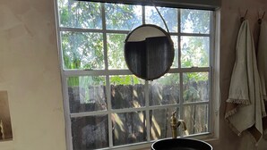 Un baño con un ventanal grande, un felpudo colgante y un lavabo.
