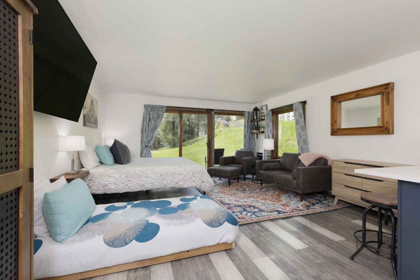 A bedroom with a bed, two sofas, a desk, and a view of the outdoors.