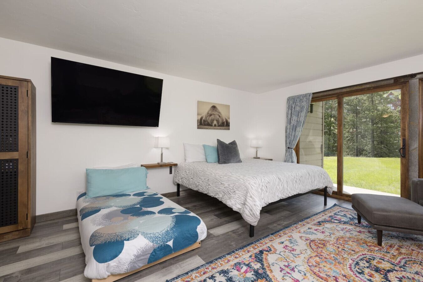 A bedroom with a bed, a sofa, a TV, and a large window.