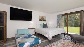 A bedroom with a bed, a sofa, a TV, and a large window.
