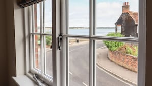 A window with a view of a road and a building across the street. - Wherry Cottage (Manningtree)