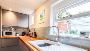 A modern kitchen with a sink, a microwave, a toaster, and a kettle. - Wherry Cottage (Manningtree)