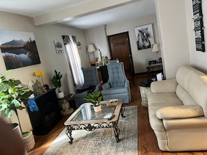 Una sala de estar con una mesa de centro de vidrio, un sofá, un sillón y una chimenea.