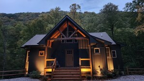 Une cabane dotée d’un porche en bois à l’avant, d’une porte d’entrée et d’un petit escalier menant à l’entrée.