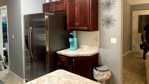 A modern kitchen with dark wooden cabinets, a stainless steel refrigerator, and a marble countertop.