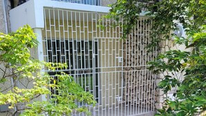 Un jardin clos, délimité par un mur de pierres, avec un bac à fleurs en béton et un petit arbre.