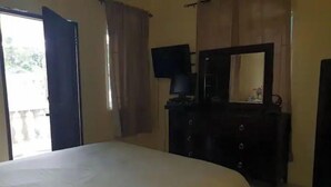 Une chambre à coucher avec un lit, une commode, une télévision et un miroir.