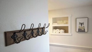 A bathroom with a wooden towel rack, a shelf with towels, and a framed picture.