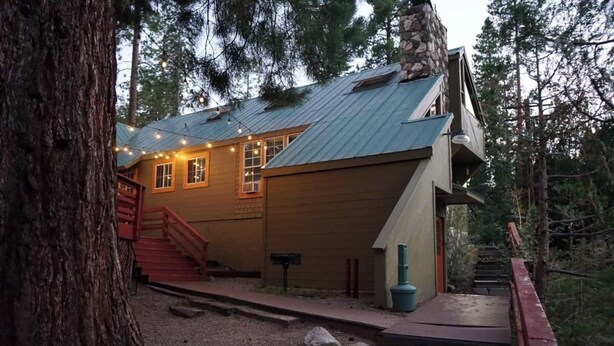 A cabin with a metal roof, wooden exterior, and a staircase leading to a deck.