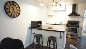 A modern kitchen with a central island, stainless steel appliances, and a large wall clock.