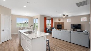 Amplia sala de estar con cocina, chimenea y televisor.