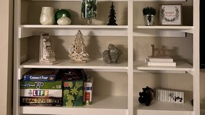 A bookshelf with decorative items and a 'COZY' sign. - New! Cottage On The Rocks, Pet Friendly, Hot Tub, Central Location (Banner Elk)