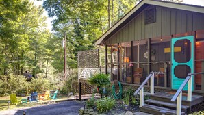 A cabin with a porch, outdoor seating, and a garden area. - New! Cottage On The Rocks, Pet Friendly, Hot Tub, Central Location (Banner Elk)