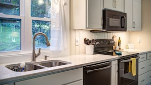 A kitchen with white cabinets, a stainless steel sink, and a black microwave. - New! Cottage On The Rocks, Pet Friendly, Hot Tub, Central Location (Banner Elk)