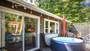 A backyard with a hot tub, a covered patio area, and a wooden deck. - New! Cottage On The Rocks, Pet Friendly, Hot Tub, Central Location (Banner Elk)