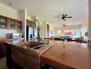A spacious kitchen with a central island, wooden cabinets, and a ceiling fan.