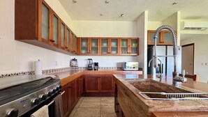 Een keuken met houten kastjes, een fornuis, een spoelbak en een koffiezetapparaat.