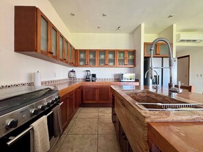 A kitchen with wooden cabinets, a stove, a sink, and a coffee maker.