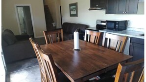 Comedor con mesa y sillas de madera, microondas y armarios oscuros.