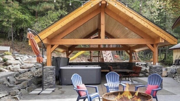 A wooden pavilion with a stone wall and a fire pit. - Kid Friendly Cabin with Mother-in-law Suite and Hot Tub! (Ronald)
