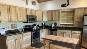 A modern kitchen with wooden cabinets, stainless steel appliances, and a central island. - Kid Friendly Cabin with Mother-in-law Suite and Hot Tub! (Ronald)