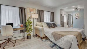 Ein modernes Hotelzimmer mit Bett, Schreibtisch, Stuhl und einer Topfpflanze.
