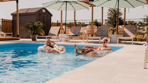 Une piscine avec des chaises longues et des parasols.
