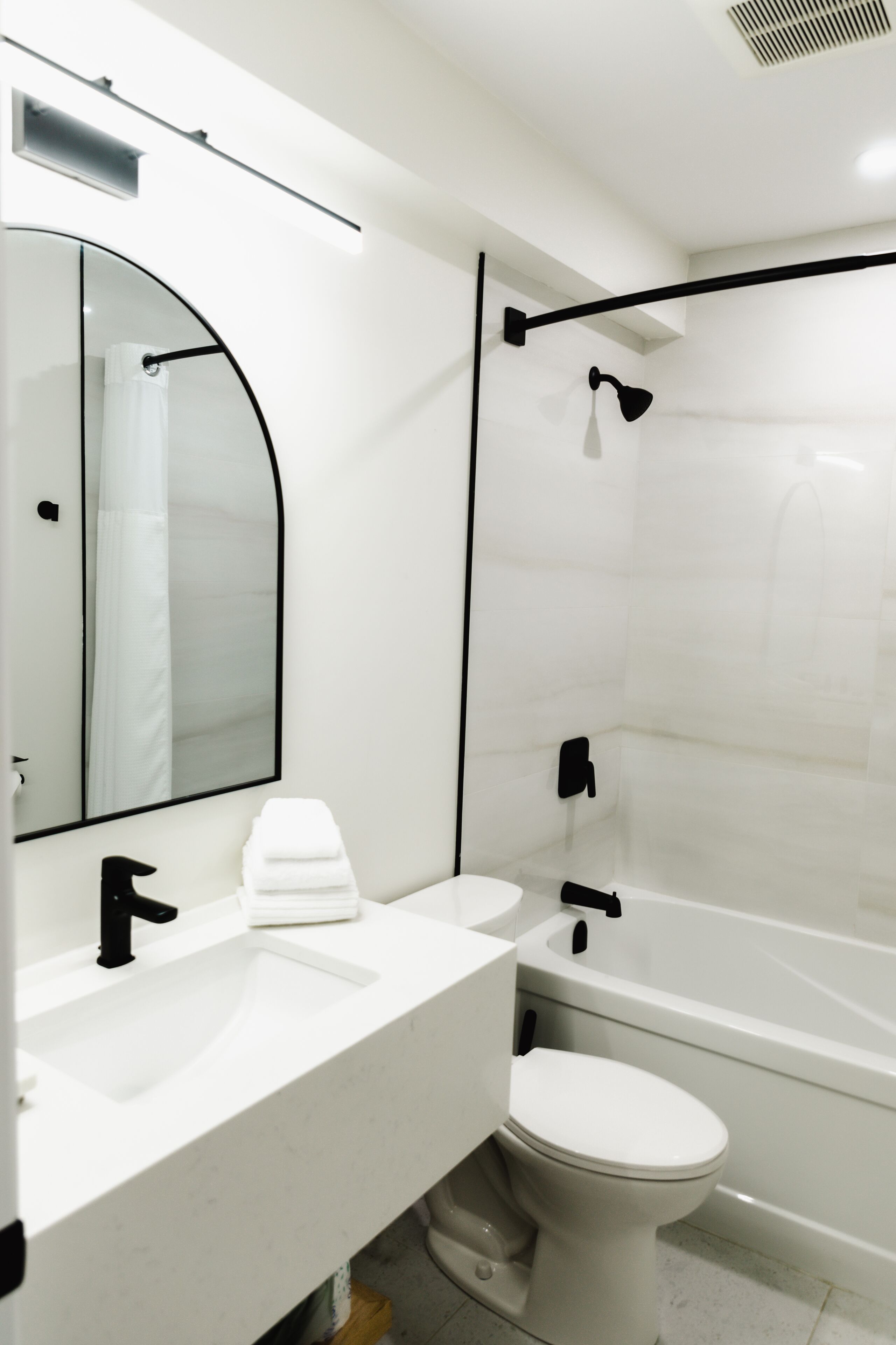 Een moderne badkamer met een wit wastafelmeubel, toilet en bad.