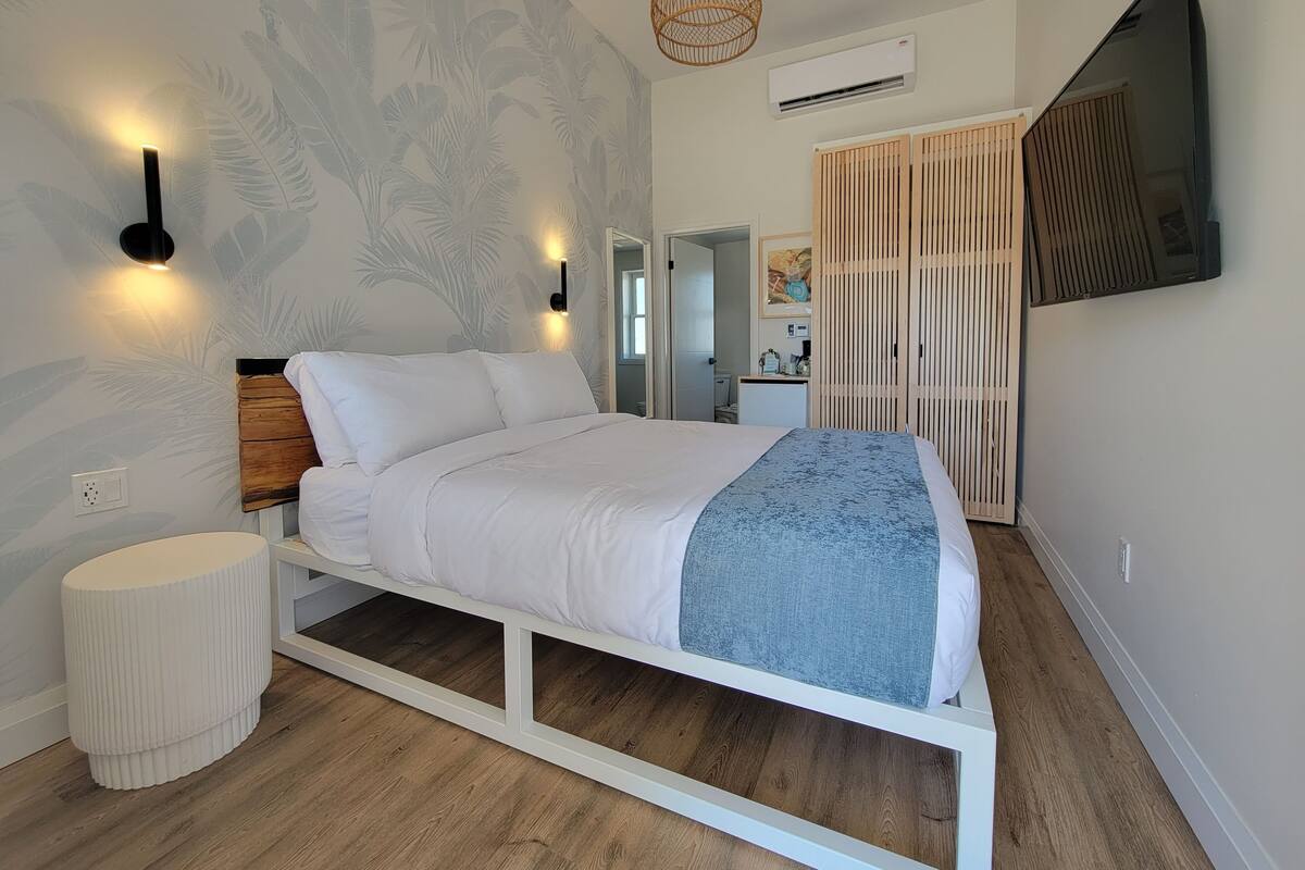Een moderne slaapkamer met een bed, wandlampen, een plafondventilator en een televisie.