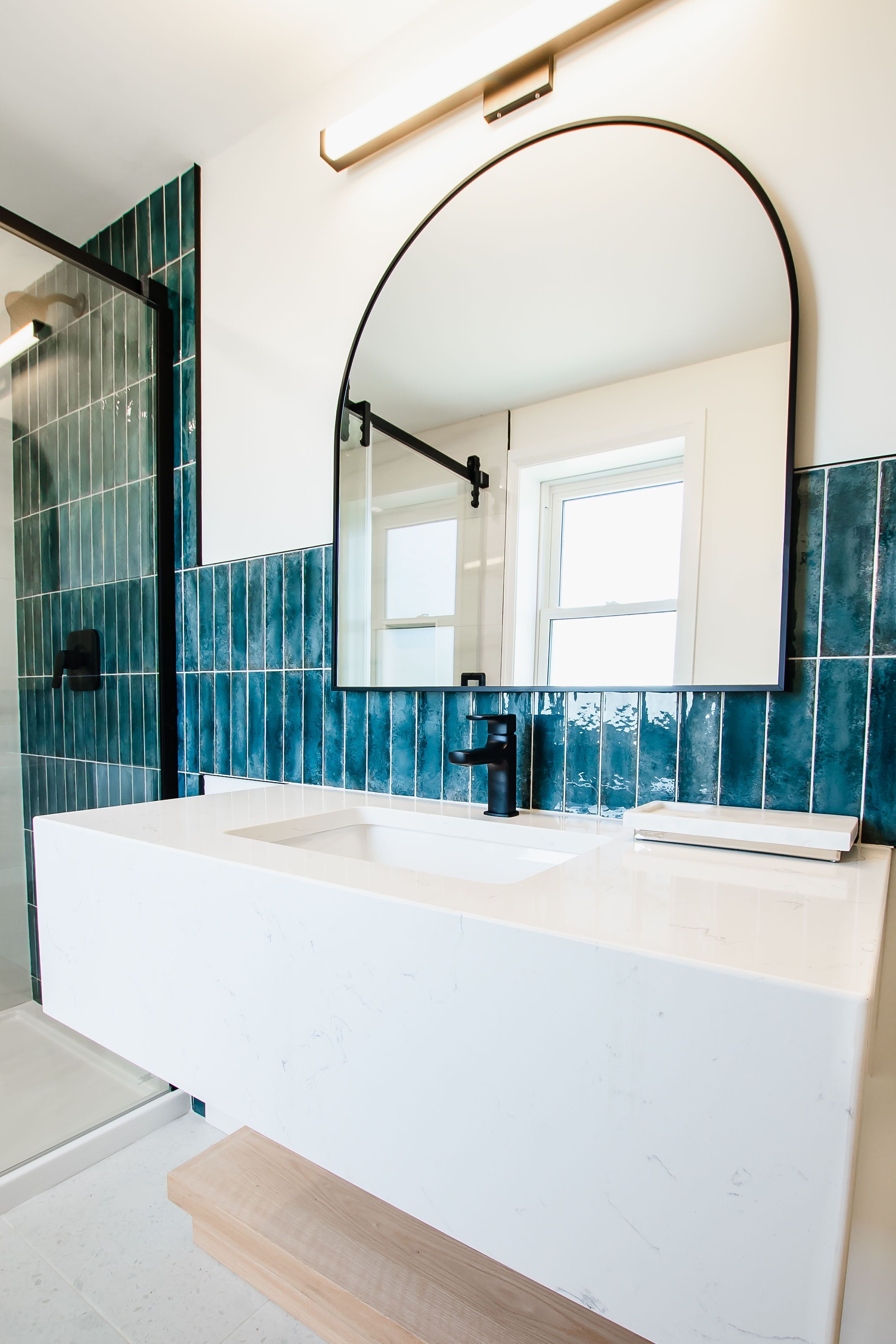 A bathroom with a white sink, black faucet, and a mirror with a black frame.