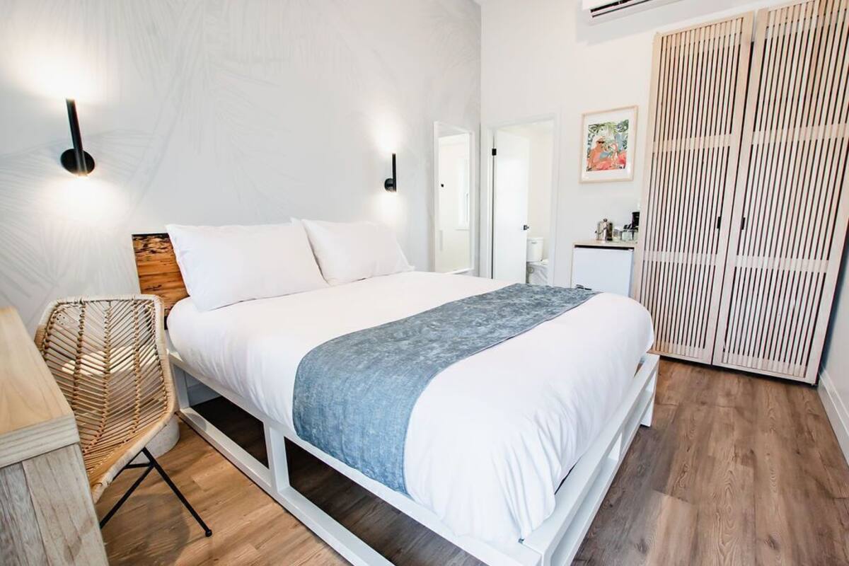 Een slaapkamer met een bed, nachtkastje, stoel en een kledingkast.