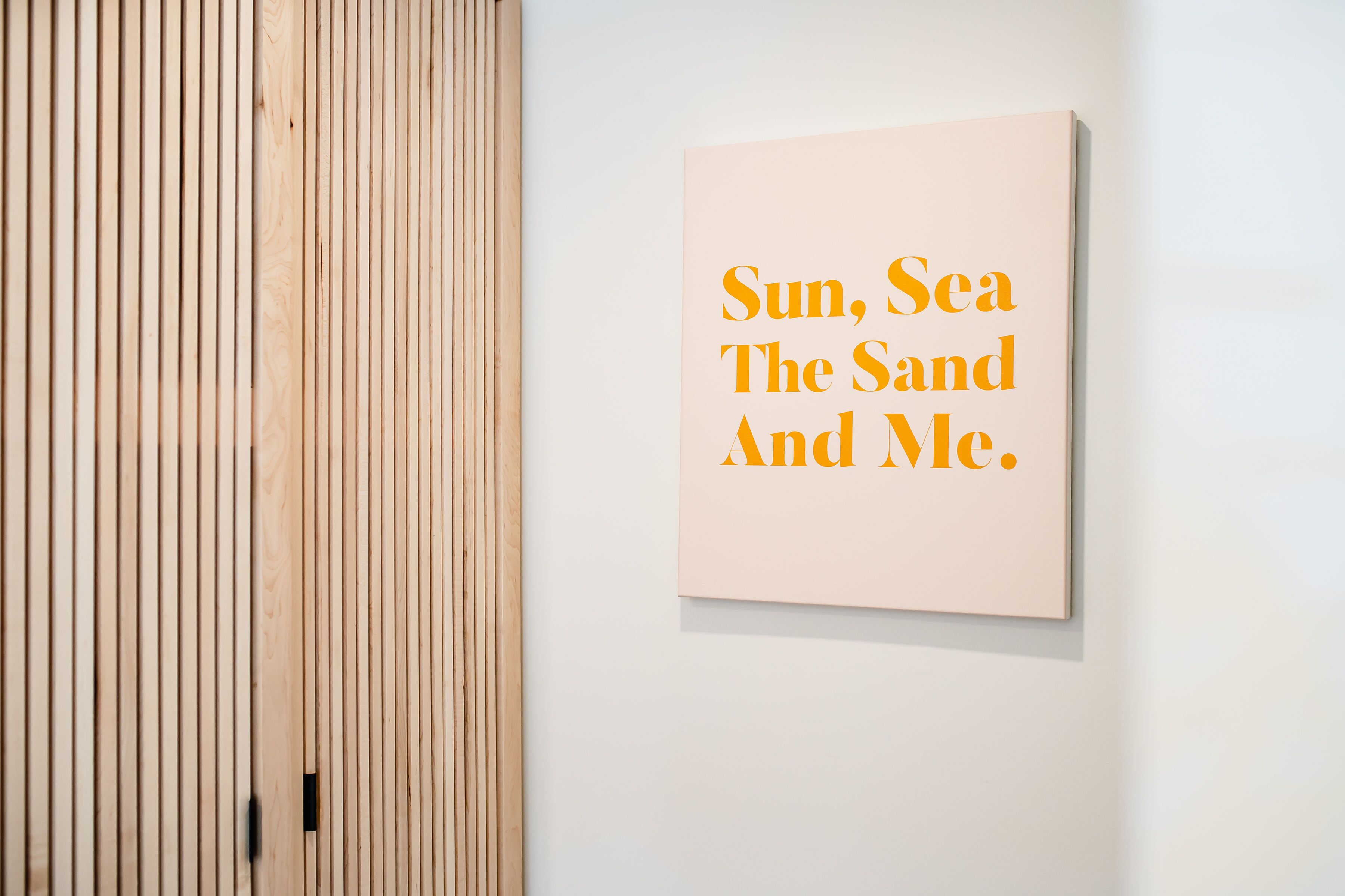 Una pared con un panel de texto que dice "Sol, mar, arena y yo."