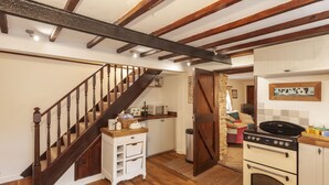 A kitchen with wooden beams, a stove, and a microwave. - Southcott Farm Cottage (Honiton)