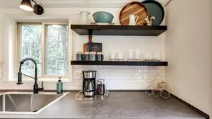 Eine moderne Küche mit Spüle aus Edelstahl, einer Kaffeemaschine und einem Weinkühlschrank.