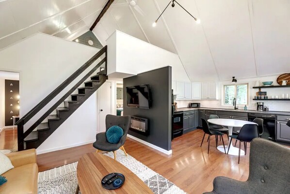 Un interior moderno con una escalera, una chimenea, un comedor y una cocina.