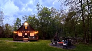 Eine Holzhütte mit Veranda, umgeben von einem Rasen und Bäumen.