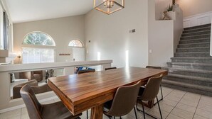 A modern kitchen with a wooden dining table, built-in seating, and a staircase leading to an upper level.