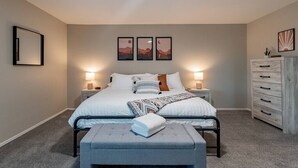 A bedroom with a bed, bedside tables, a dresser, and wall art.
