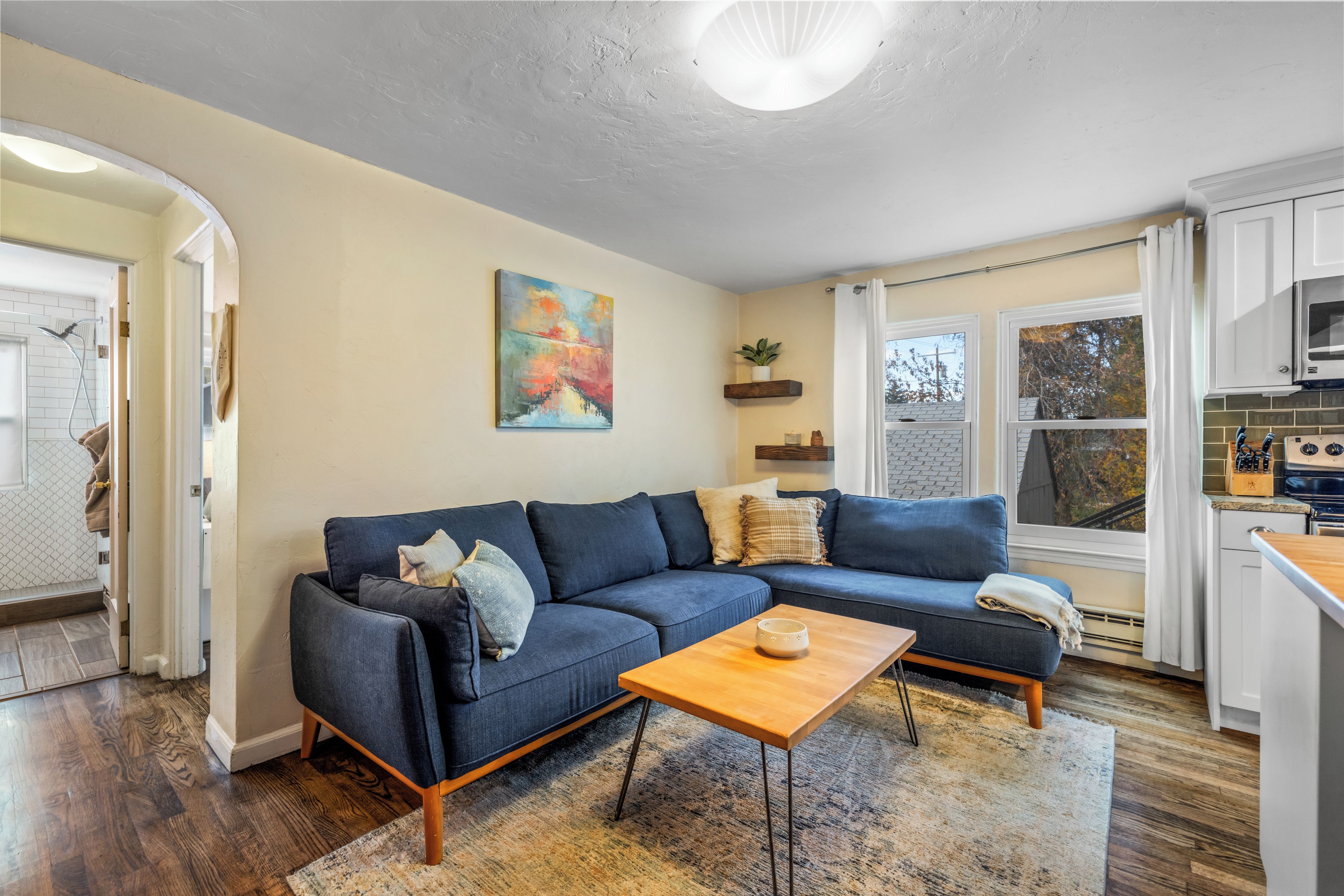 Un salon moderne avec un canapé d’angle, une table basse et un tableau accroché au mur.